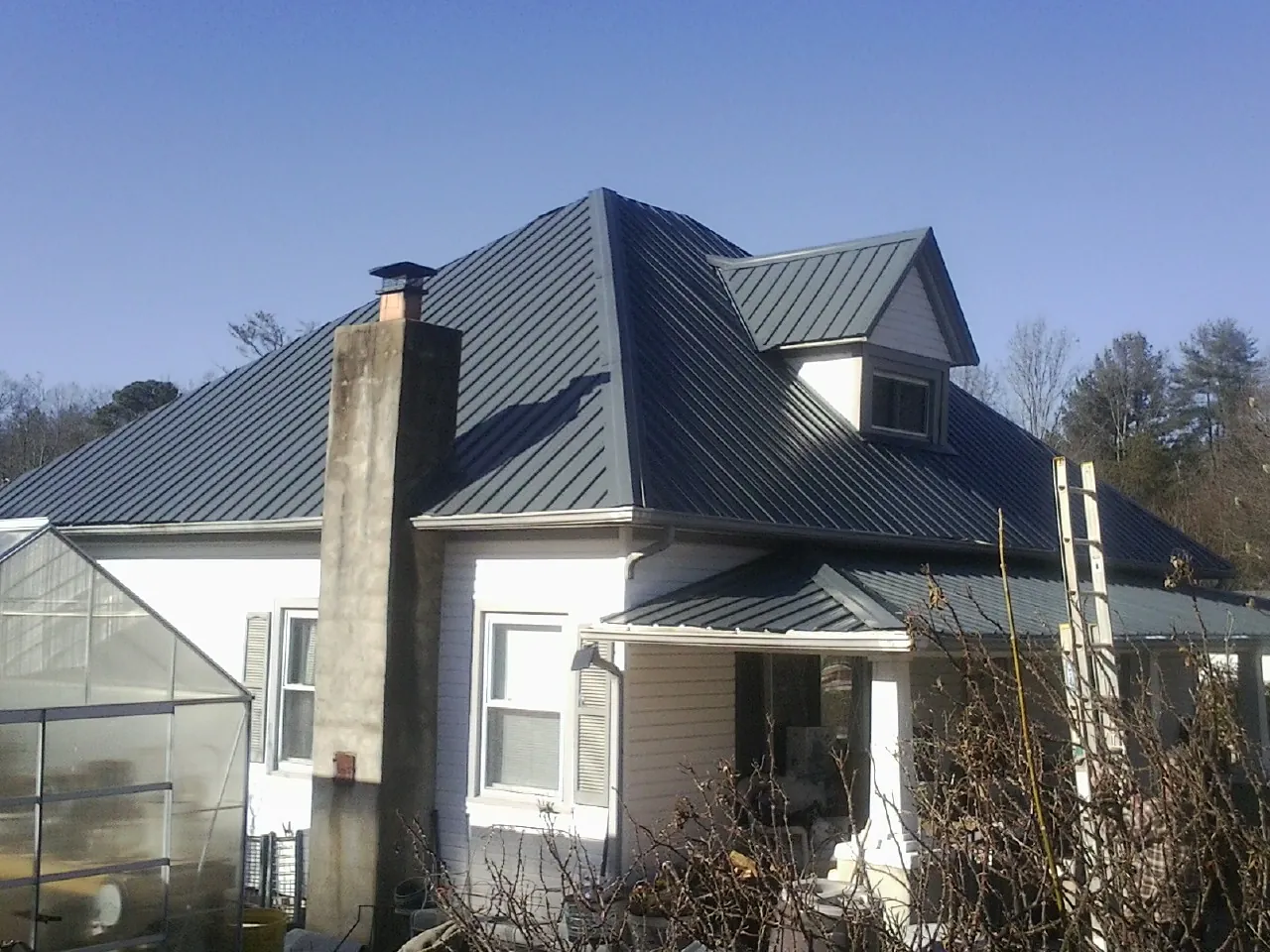 Dark blue standing seam metal roof on a white farmhouse with dormer — Slate & Tile Roof Repair by Roofing Brothers in Monroeville